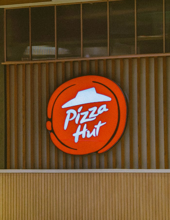 A sign for pizza hut is shown on the side of a building